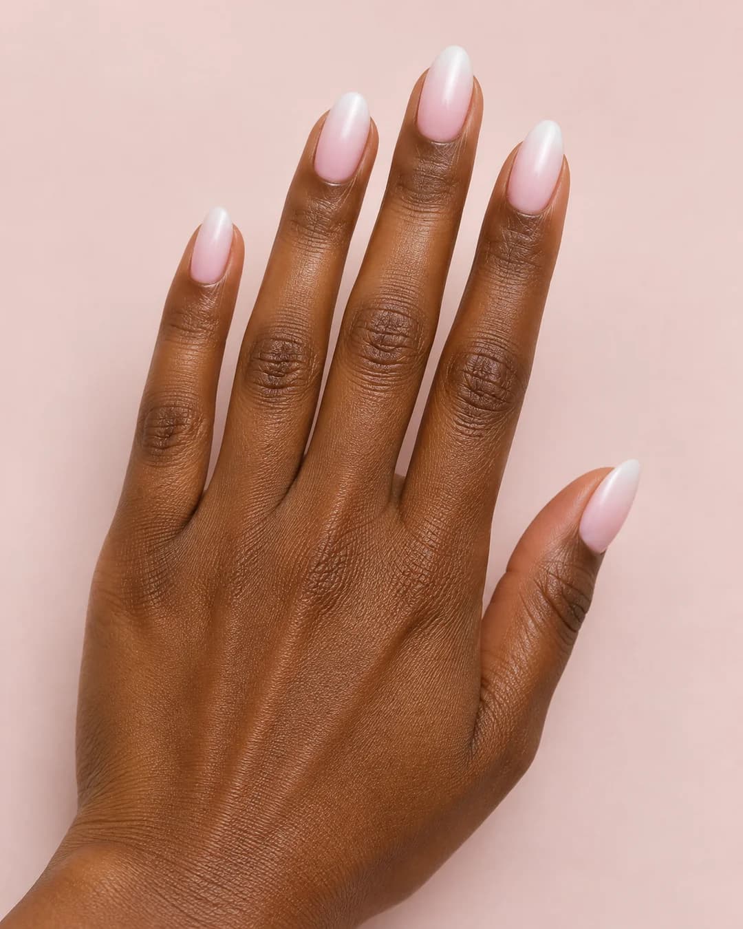 Uñas almendradas de largo medio con degradado de rosa a blanco lechoso y acabado satinado. Detalle de las uñas.