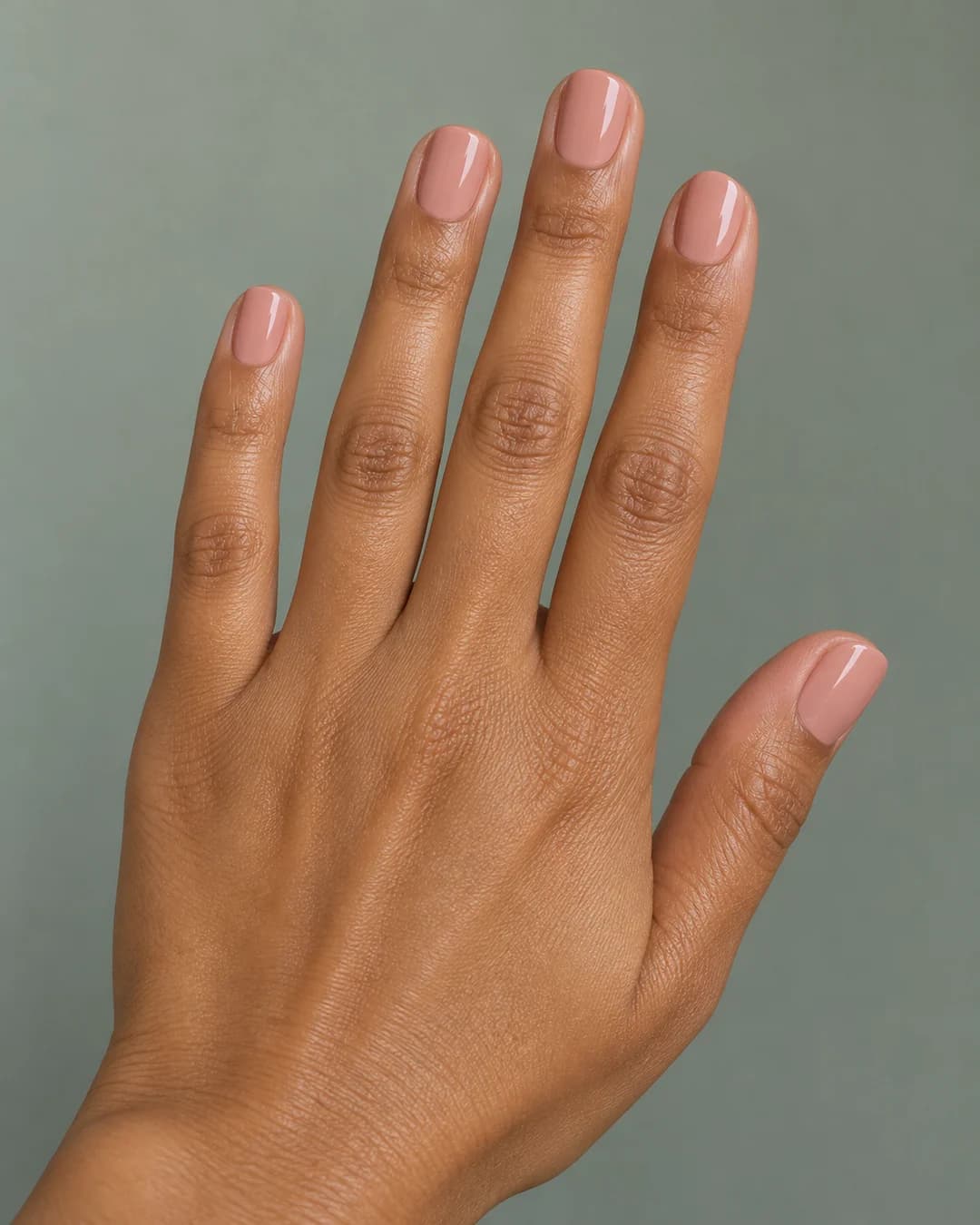 Uñas cortas redondas con color nude rosado uniforme y acabado brillante. Detalle de las uñas.