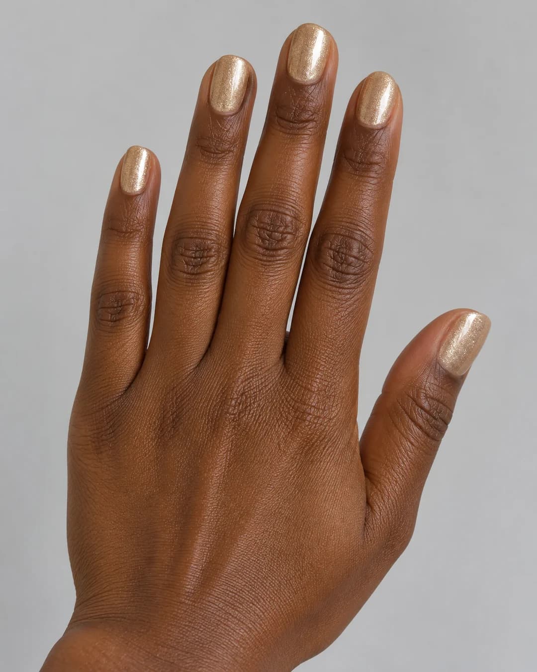 Uñas cortas ovaladas en dorado champán con destellos finos. Detalle de las uñas.