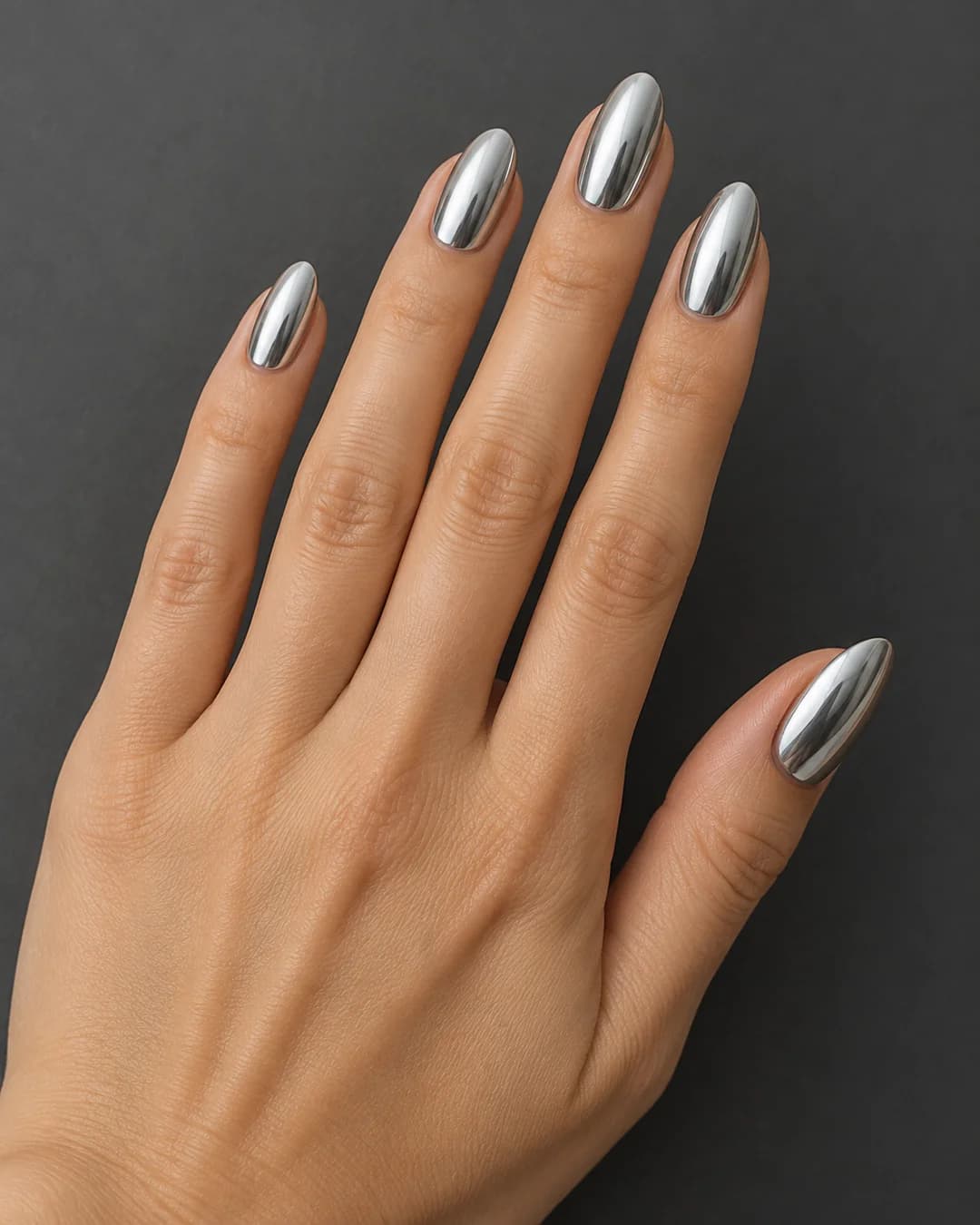 Uñas almendradas de largo medio en plateado con reflejo espejo. Detalle de las uñas.