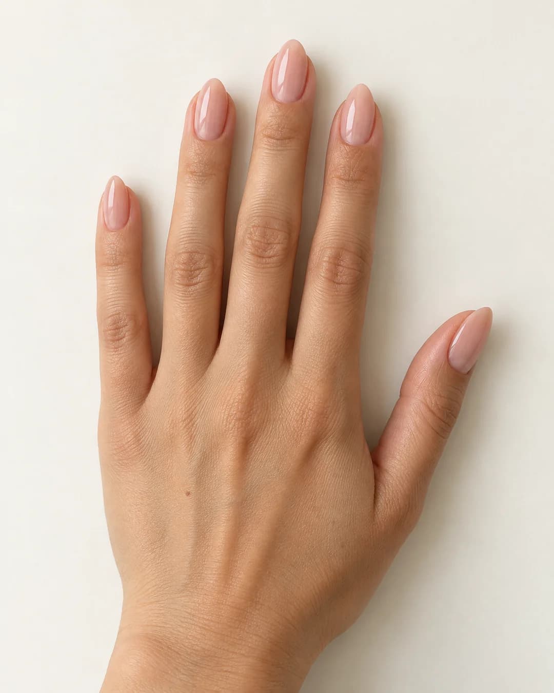 Uñas de forma almendrada y longitud media, en nude rosado translúcido de acabado brillante. Detalle de las uñas.