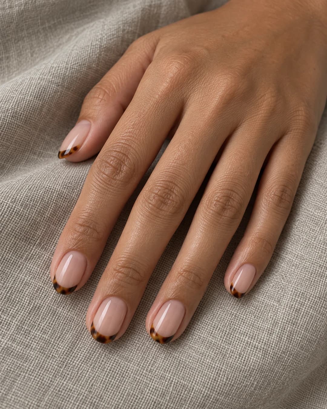 Uñas cortas almendradas con base rosa nude y micro-french carey en ámbar, miel y chocolate.