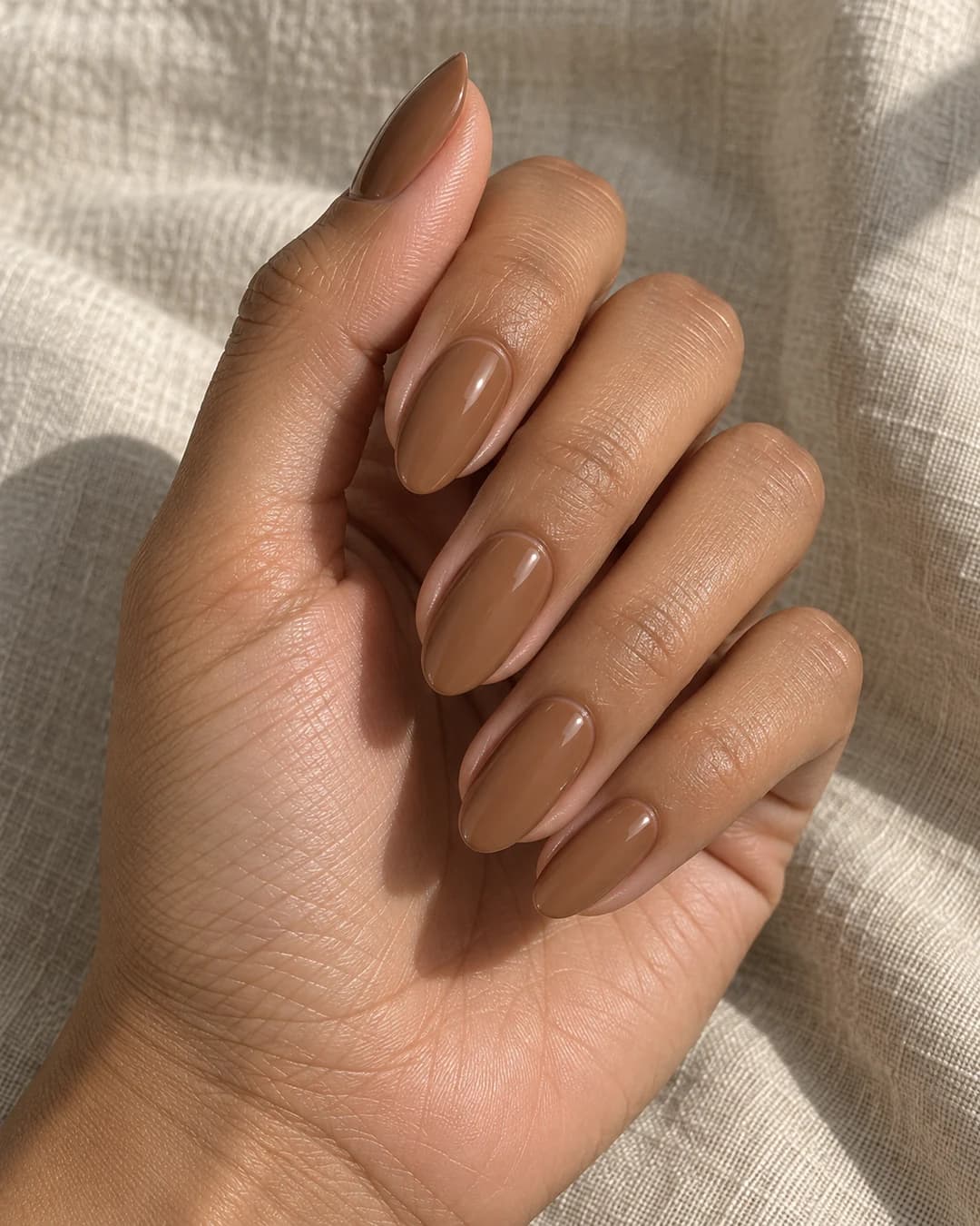 Uñas almendradas medias en tan canela chai latte sobre piel oliva.
