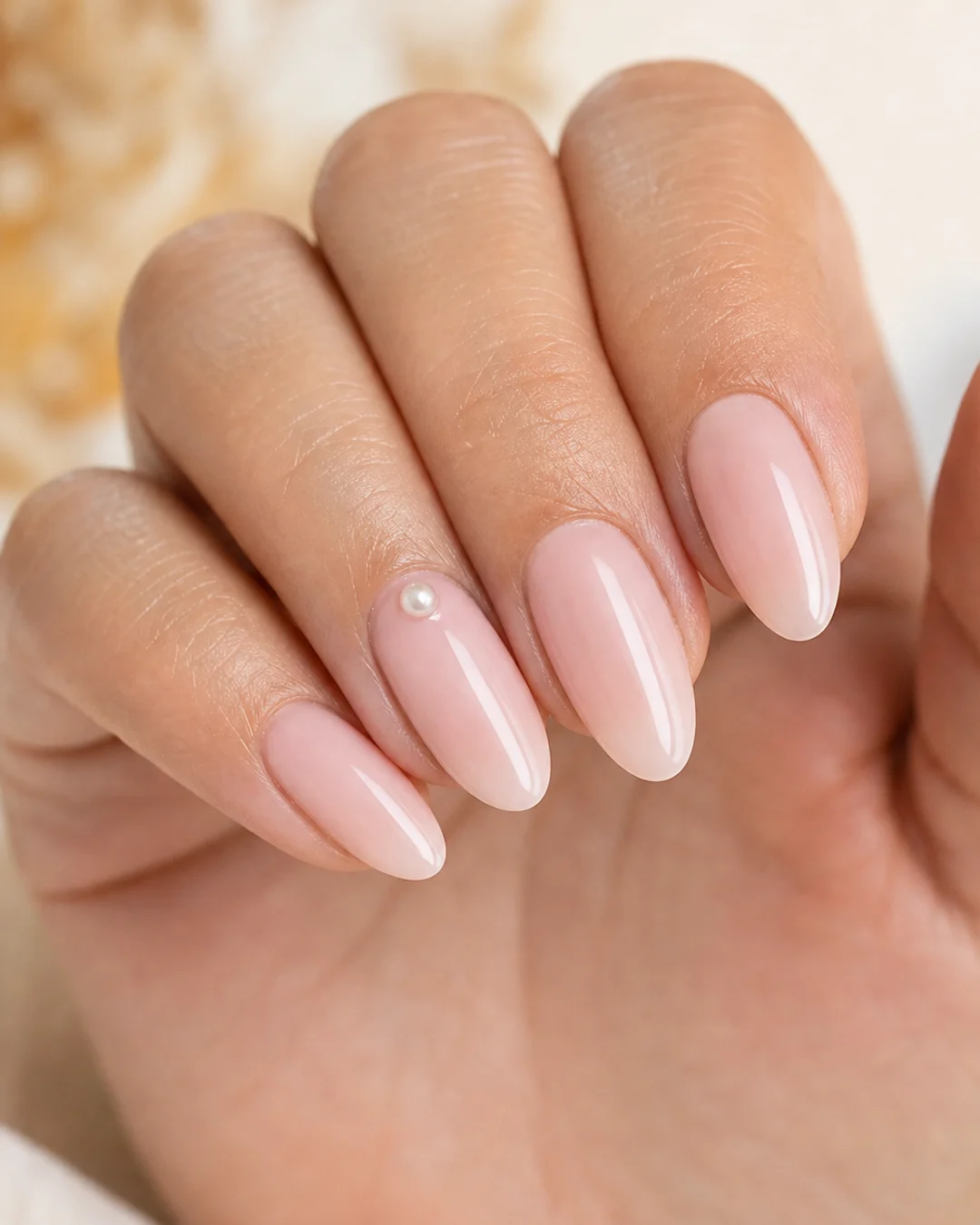 Uñas nude con una micro perla decorativa en la cutícula del anular