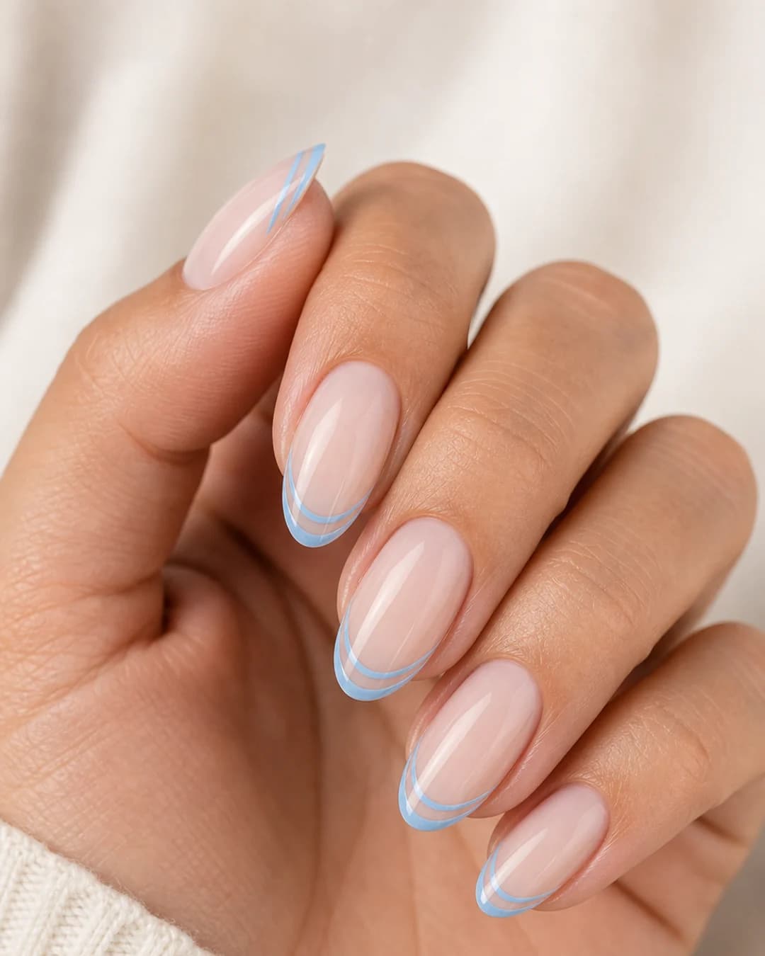Uñas con doble línea de francesa azul cielo sobre base nude lechosa
