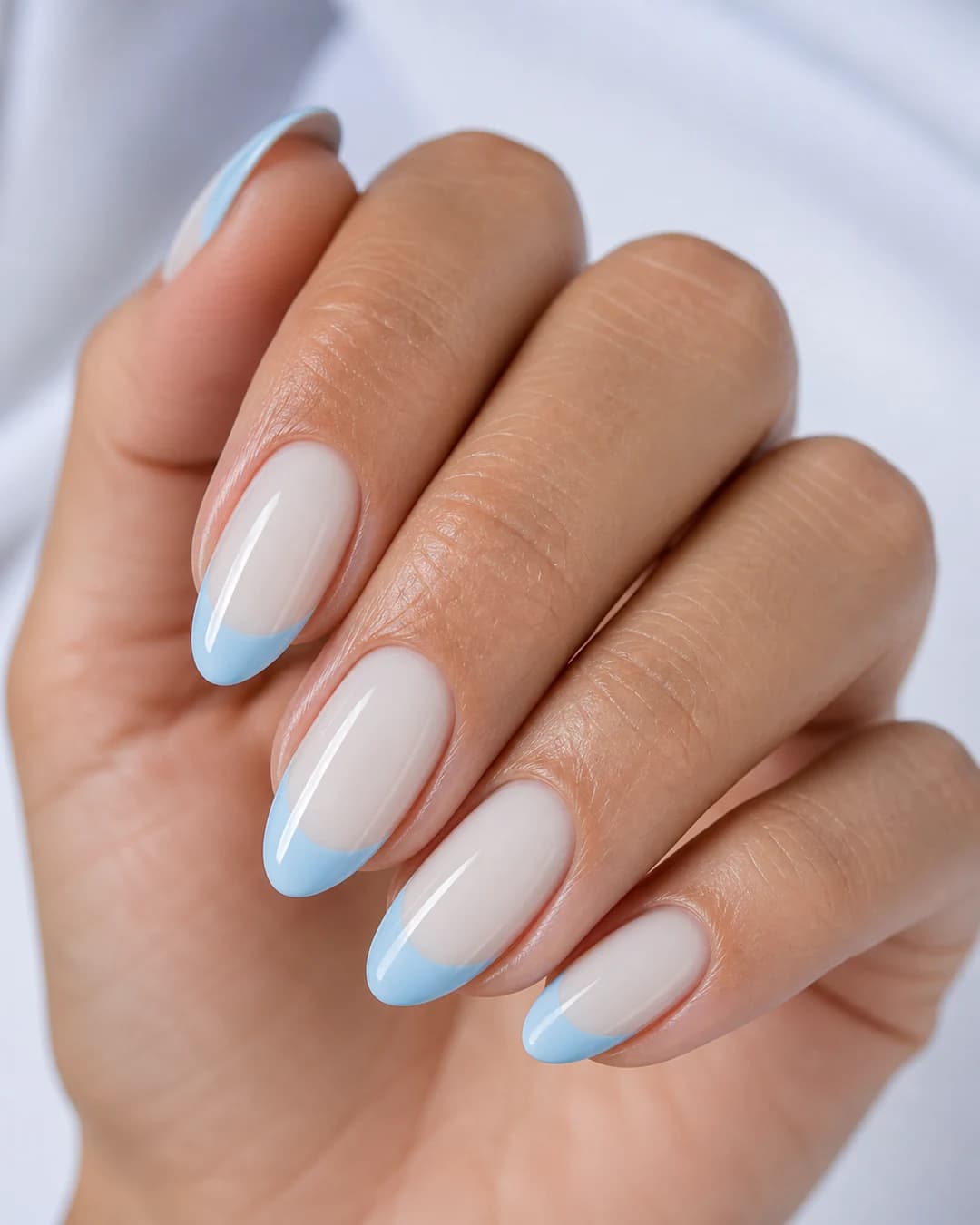 Manicura francesa con punta azul cielo pastel sobre base lechosa en forma almendrada