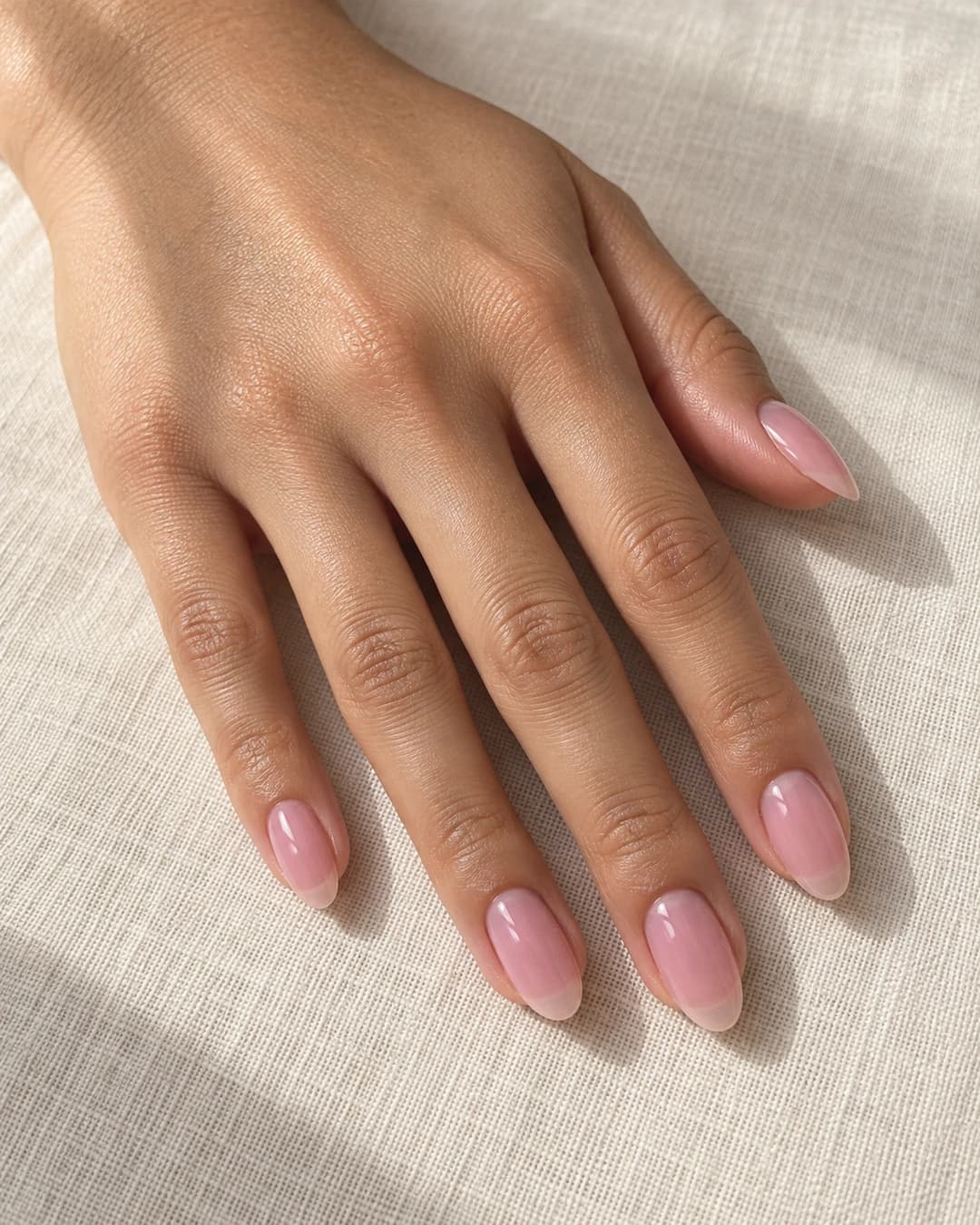 Uñas almendradas medias con base rosa lechosa translúcida; la línea natural se distingue suavemente.