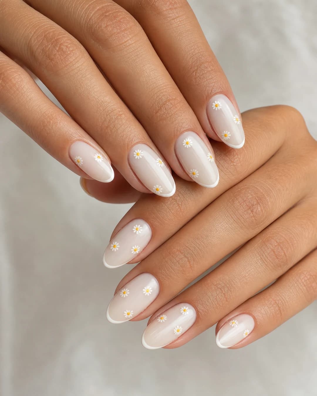 Uñas almendradas con francesa microline blanca y mini margaritas distribuidas sobre la base lechosa