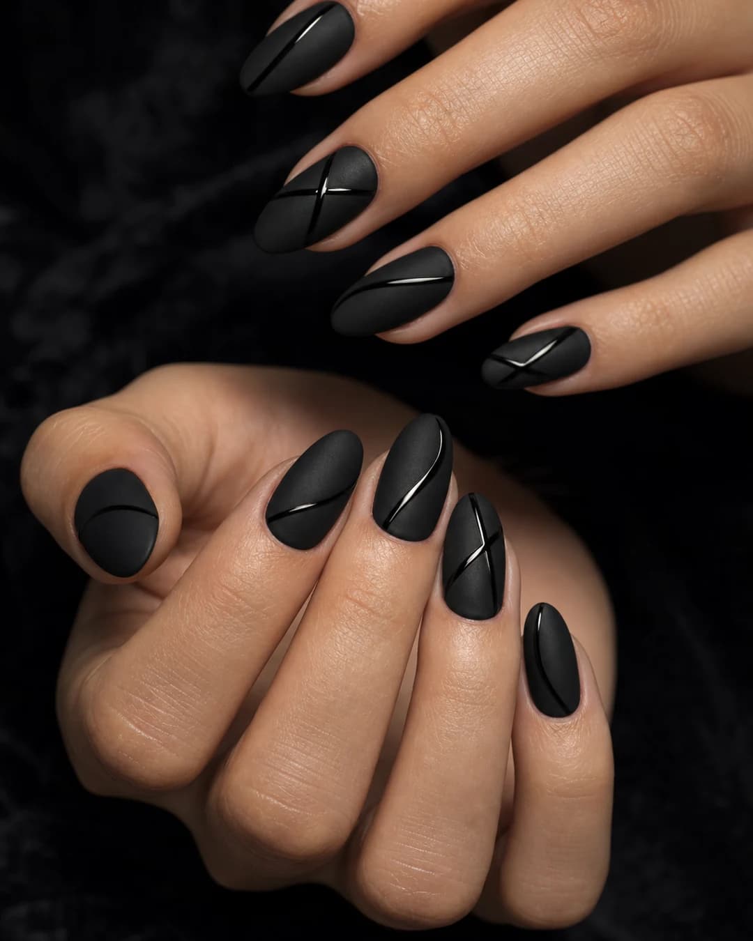 Uñas almendradas en negro mate aterciopelado con líneas glossy negras sobre cada uña