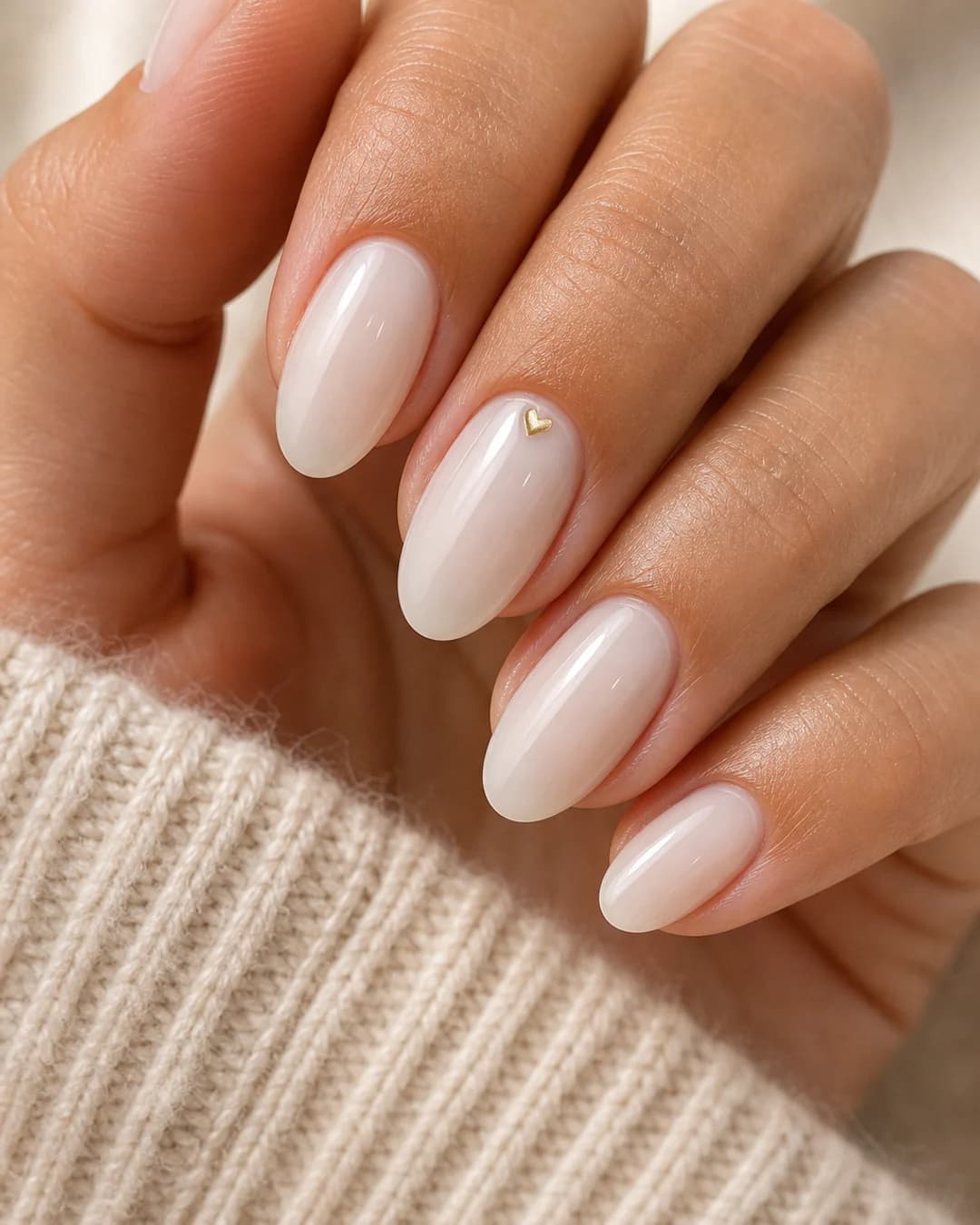 Uñas lechosas con un mini corazón dorado pintado en la lúnula del anular