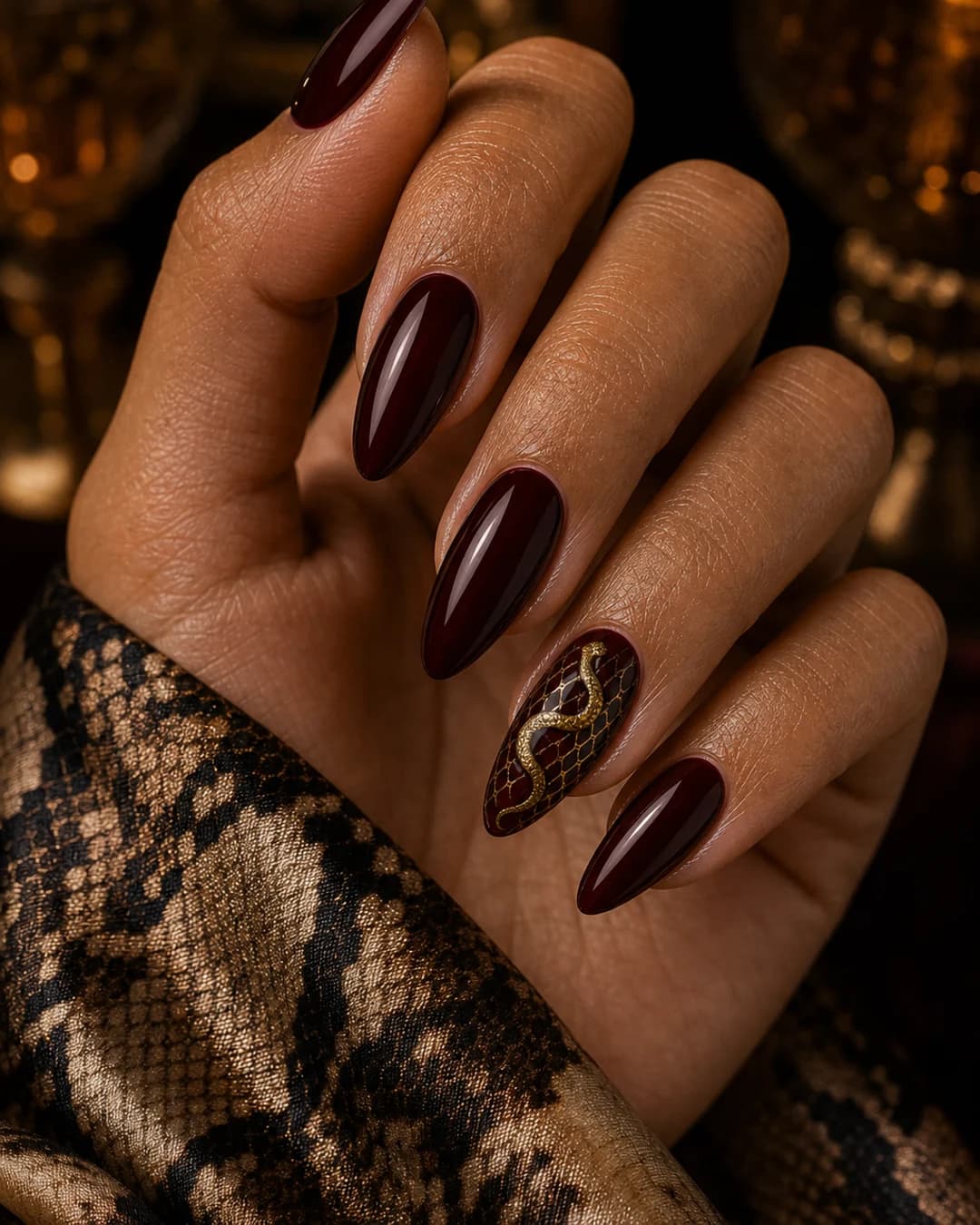 Uñas oxblood con micro estampado serpiente dorado en el anular mob wife