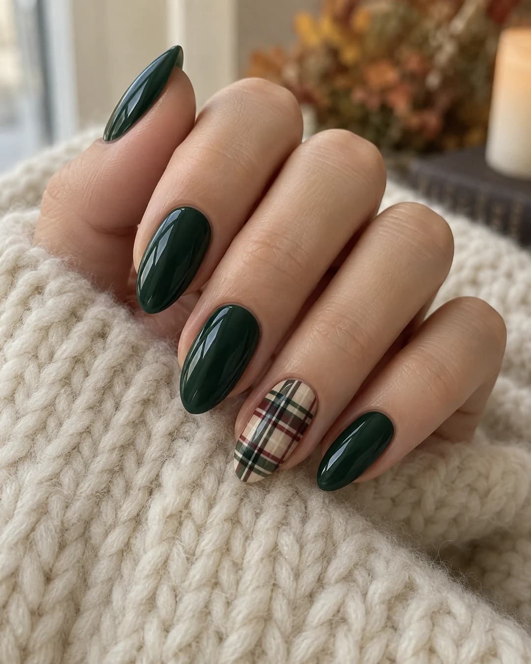 Mano de piel clara con uñas almendradas medias verde pino y un acento tartán merlot, crema y verde.
