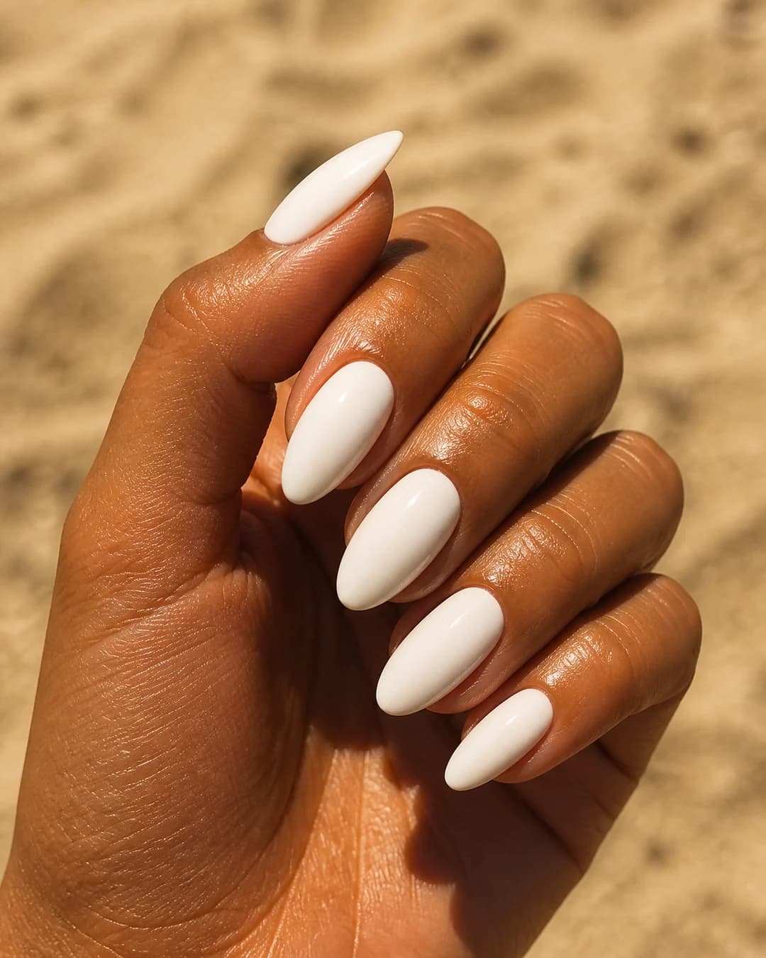 Uñas almendradas en blanco roto sobre piel bronceada de verano