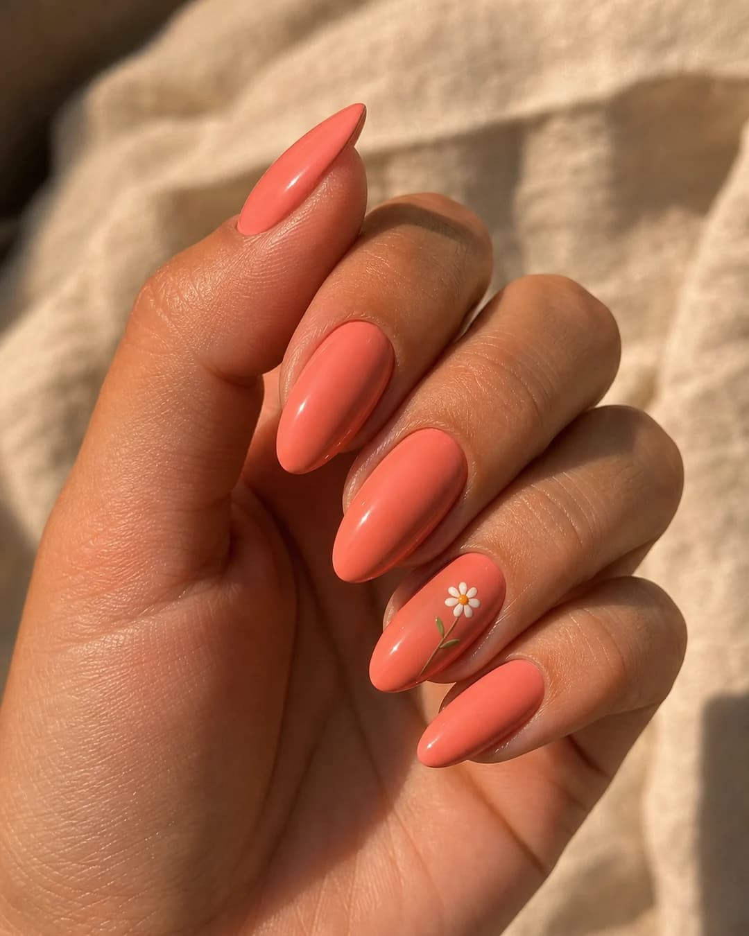 Uñas en coral suave con una micro flor blanca pintada a mano en el anular