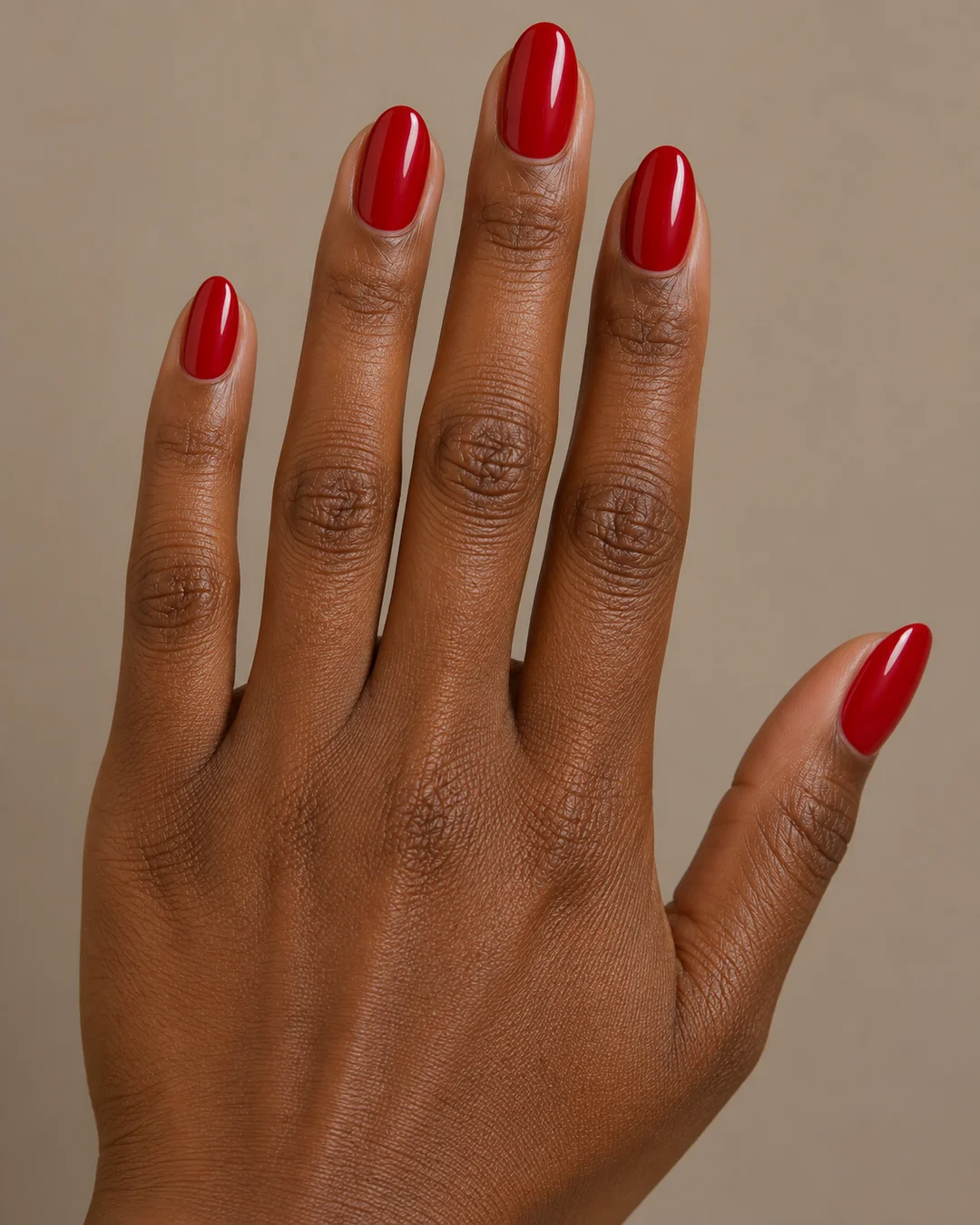 Uñas ovaladas medias en rojo cereza uniforme y brillante. Detalle de las uñas.