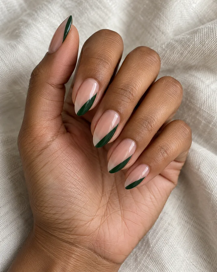 Uñas almendradas nude con una curva verde oscuro en un lateral.