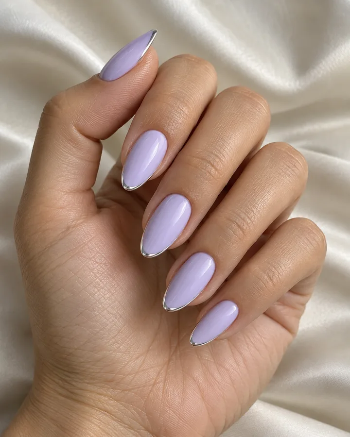 Uñas almendradas lilas con un filo plateado en la punta.