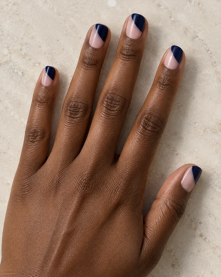 Uñas squoval con bloques diagonales azul oscuro y parte de la base nude visible.